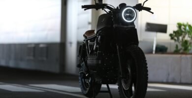 A sleek cafe racer motorcycle parked indoors with strong lighting contrast.